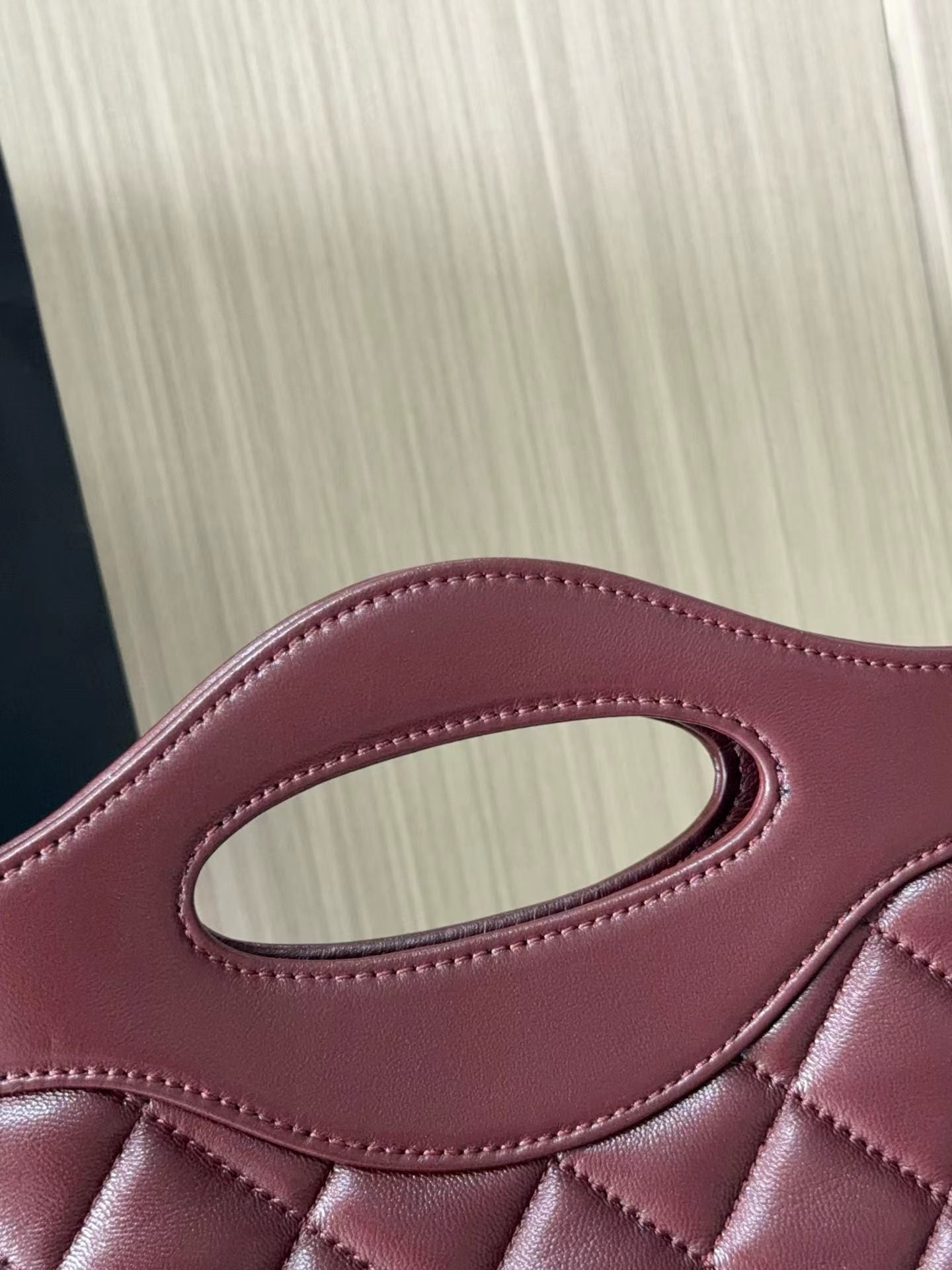 Burgundy quilted mini handbag handle detail